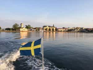 Swedish flag on a boat with buildings in the backgroun